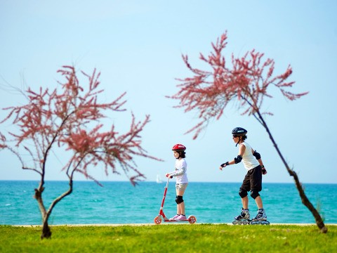Due bambini con monopattino e pattini a rotelle vicino al mare ad Aminess Planet Camping Sirena, Istria, Croazia.