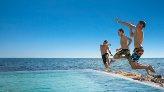 Drei Jungen springen in den Pool mit Blick auf das Meer im Aminess Planet Camping Sirena, Istrien, Kroatien.