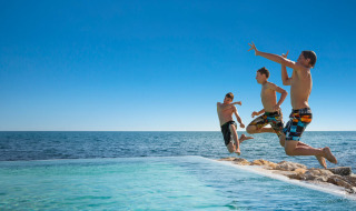 Drie jongens springen in een zwembad bij zee bij Aminess Planet Camping Sirena in Istrië, Kroatië.