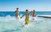 Kids running and splashing in shallow water at Aminess Planet Camping Sirena, a holiday park in Istria, Croatia.