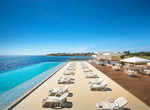Infinity-Pool mit Liegestühlen und Terrasse am Meer im Aminess Planet Camping Sirena, Istrien, Kroatien.
