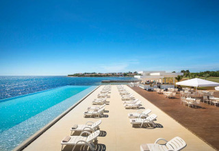 Udsigt over infinity-pool, liggestole og terrasse ved havet på Aminess Planet Camping Sirena i Istrien, Kroatien.