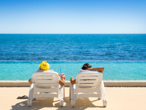 Twee personen relaxen op ligstoelen aan het zwembad met uitzicht op zee op Aminess Planet Camping Sirena.