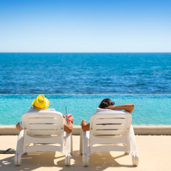 Zwei Personen entspannen auf Liegestühlen am Pool mit Meerblick im Aminess Planet Camping Sirena, Istrien.