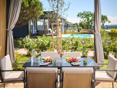 Tavolo da colazione all'aperto con sedie e vista su piscina e giardino in un villaggio in Istria, Croazia.