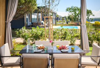 Outdoor breakfast table with juice, fruit, and pastries overlooking a garden and pool in Istria, Croatia.