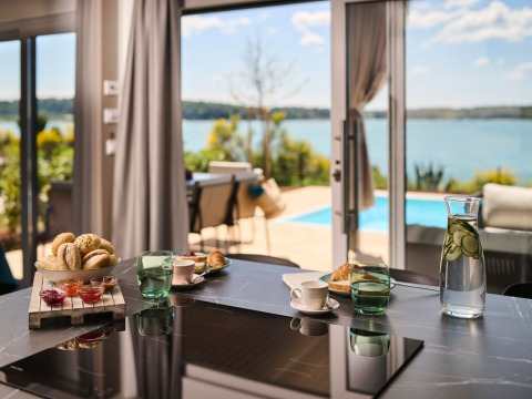 Table du petit déjeuner avec pains, confitures et eau au concombre, vue sur piscine et mer en Istrie.
