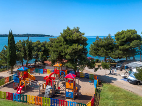 Aire de jeux avec clôture colorée au bord de la mer à Aminess Planet Camping Sirena en Istrie, Croatie.