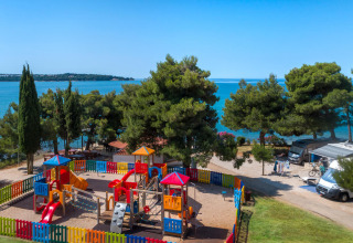 Aire de jeux avec clôture colorée au bord de la mer à Aminess Planet Camping Sirena en Istrie, Croatie.