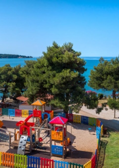 Spielplatz mit buntem Zaun am Meer im Aminess Planet Camping Sirena Ferienpark in Istrien, Kroatien.