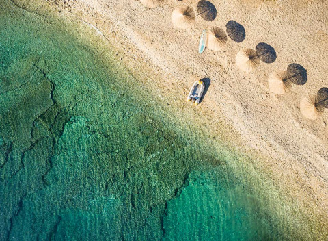 Luftaufnahme vom Strand des Aminess Planet Camping Sirena mit Sonnenschirmen und klarem Wasser in Istrien.