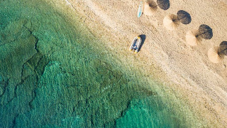 Luftaufnahme vom Strand des Aminess Planet Camping Sirena mit Sonnenschirmen und klarem Wasser in Istrien.