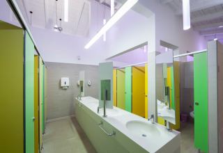 Modern communal bathroom with colorful stall doors and sinks at Aminess Planet Camping Sirena, Istria, Croatia.