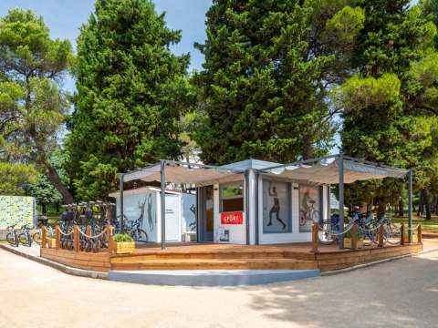 Centro sportivo ad Aminess Planet Camping Sirena in Istria, Croazia, con biciclette e pini sullo sfondo.