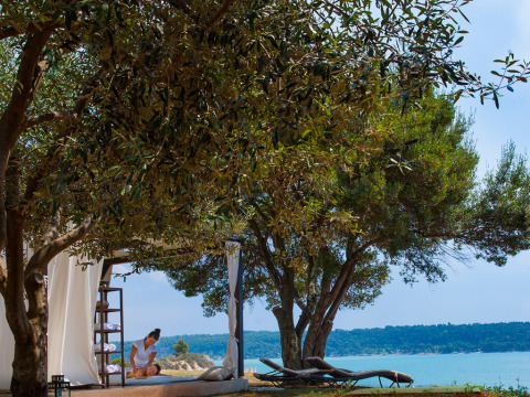 Buitenmassage onder bomen met zicht op de zee bij Aminess Planet Camping Sirena, Istrië, Kroatië.