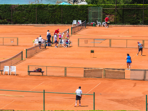 Persone giocano a tennis sui campi in terra rossa di Aminess Planet Camping Sirena in Istria, Croazia.