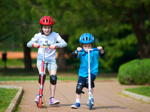 Due bambini con caschi e ginocchiere vanno in monopattino ad Aminess Planet Camping Sirena in Istria, Croazia.