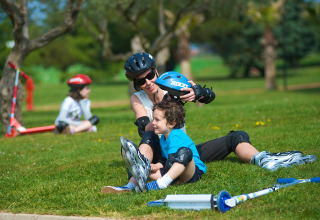 Gezin met kinderen op rolschaatsen en helmen geniet van een dag in het park bij Aminess Planet Camping Sirena.