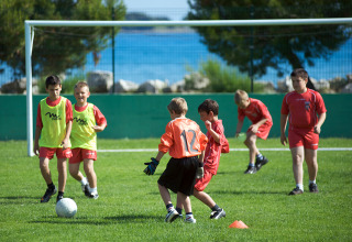 Bambini giocano a calcio su un campo verde all’Aminess Planet Camping Sirena, in Istria, Croazia, vicino al mare.