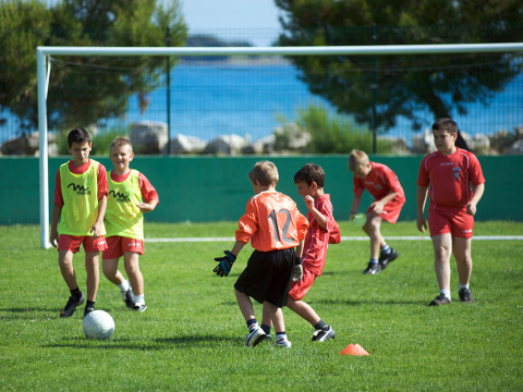 Bambini giocano a calcio su un campo verde all’Aminess Planet Camping Sirena, in Istria, Croazia, vicino al mare.