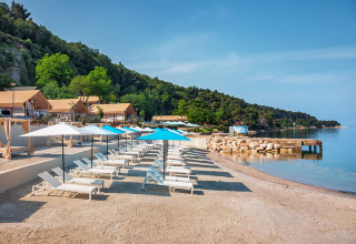 Transats et parasols sur la plage du Valamar Camping Lanterna à Istrie, Croatie, au bord de la mer calme.