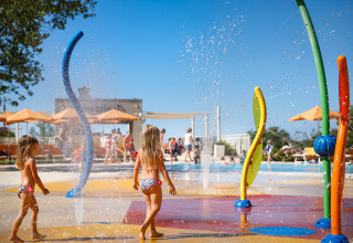 Children playing in a colorful splash park with fountains at Valamar Camping Lanterna, Istria, Croatia.