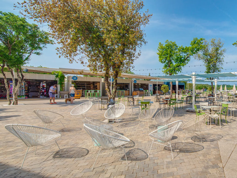 Buitenzitruimte met moderne stoelen en bomen bij Valamar Camping Lanterna, vakantiepark in Istrië, Kroatië.