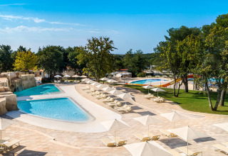 Outdoor swimming pool and sun loungers with umbrellas at Valamar Camping Lanterna holiday park in Istria, Croatia.