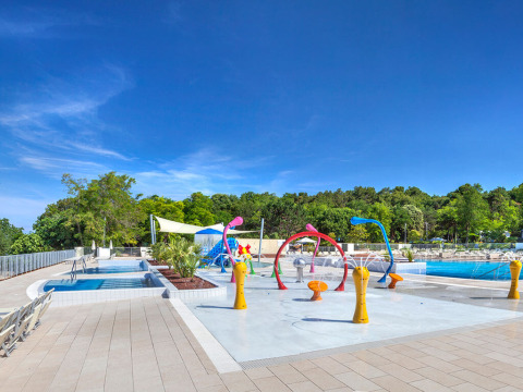 Außenpool und bunte Wasserspielzone im Valamar Camping Lanterna Ferienpark in Istrien, Kroatien, unter blauem Himmel.