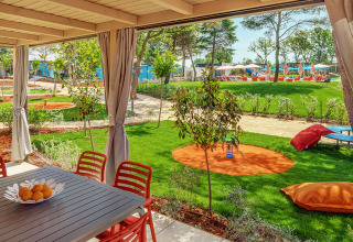 Blick aus dem Maro Home Chalet im Valamar Camping Lanterna, mit Terrasse, Gartentisch und Spielbereich.
