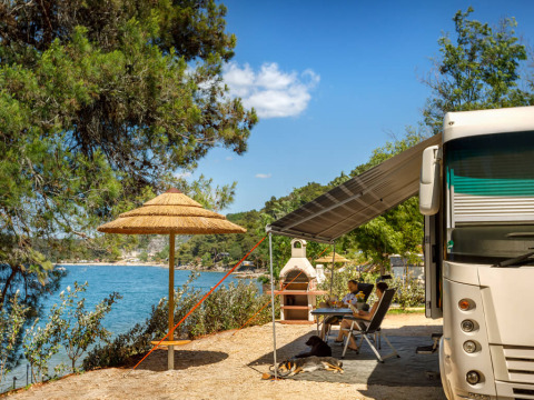 Seaside camping at Valamar Camping Lanterna in Istria, Croatia, featuring an RV, outdoor seating, and two dogs.