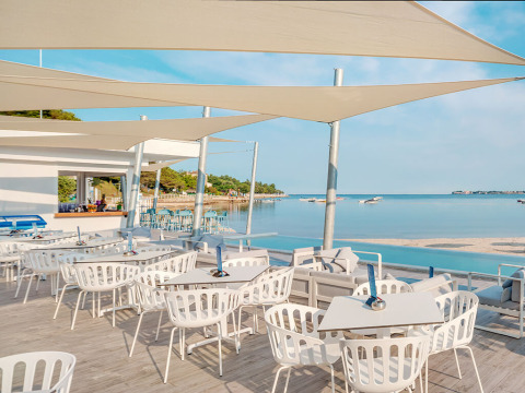 Restaurantterrasse am Meer mit weißen Stühlen bei Valamar Camping Lanterna, Istrien, Kroatien.