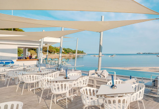 Restaurantterrasse am Meer mit weißen Stühlen bei Valamar Camping Lanterna, Istrien, Kroatien.