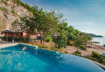 Vista de piscina infinita con tiendas safari, árboles y costa en Valamar Camping Lanterna, Croacia.