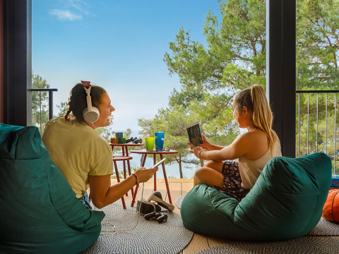 Dos jóvenes se relajan en puff disfrutando la vista en Valamar Camping Lanterna en Istria, Croacia.