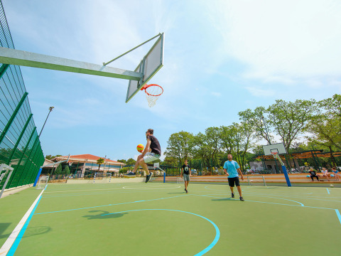 Basketbalspeler springt richting basket op het buitenterrein van Valamar Camping Lanterna, Istrië, Kroatië.