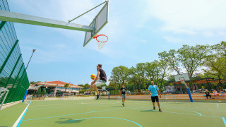 Un giocatore salta verso il canestro su un campo da basket a Valamar Camping Lanterna, Istria, Croazia.