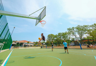 A player jumps toward the hoop on an outdoor basketball court at Valamar Camping Lanterna holiday park, Istria.