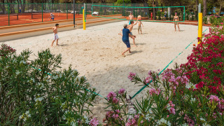 Ospiti giocano a beach volley al Valamar Camping Lanterna con campi da tennis e fiori in Istria, Croazia.