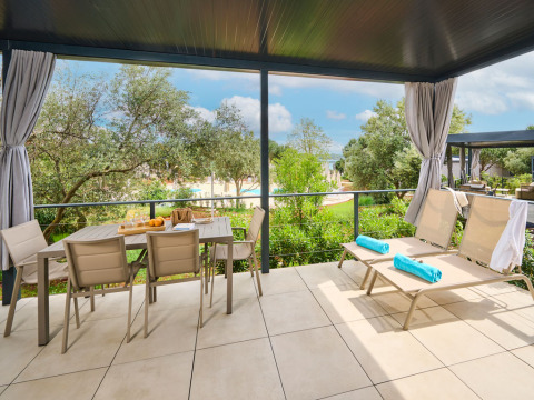 Covered terrace at Premium Holiday Home, Aminess Planet Camping Sirena, Croatia, with chairs, table and loungers.
