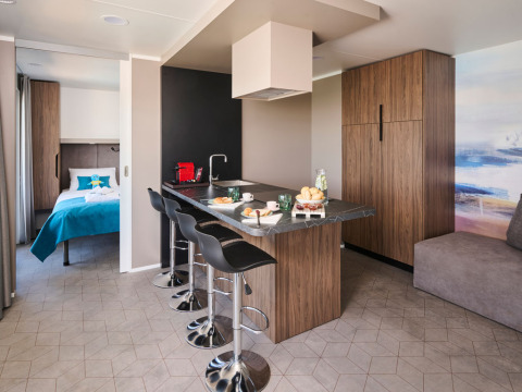 Luxe vakantiewoning met moderne keuken, barkrukken en uitzicht op een stijlvolle slaapkamer.