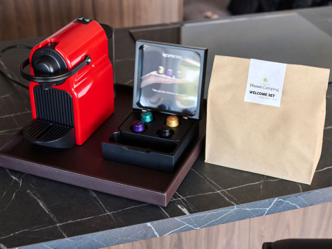 Macchina da caffè Nespresso rossa, capsule e kit di benvenuto su un ripiano in una casa vacanze in Croazia.