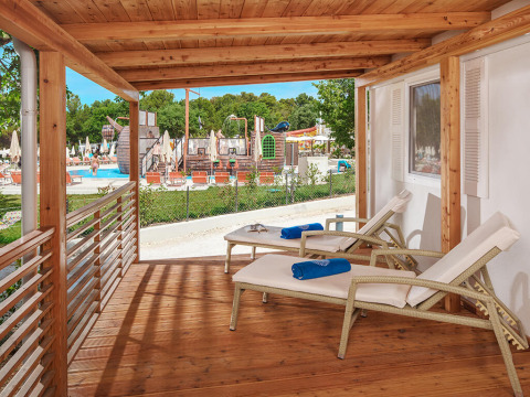Terrazza in legno con lettini al chalet Istrian Home nel Valamar Camping Lanterna, Croazia, vista piscina.