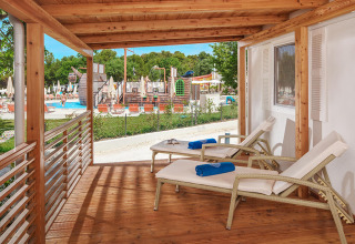 Terrazza in legno con lettini al chalet Istrian Home nel Valamar Camping Lanterna, Croazia, vista piscina.