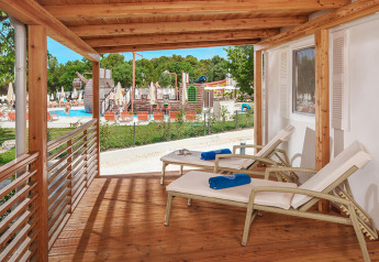 Houten terras met ligstoelen bij Istrian Home chalet op Valamar Camping Lanterna, Kroatië, zicht op zwembad.