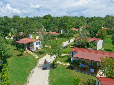 Vista aerea dei chalet Istrian Home con tetti rossi, circondati da alberi verdi e sentieri erbosi.