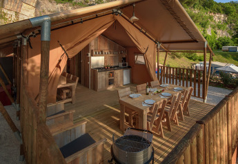 Tenda safari glamping al Valamar Camping Lanterna, Croazia, con zona pranzo esterna e cucina rustica.