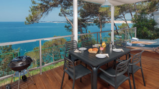 Terrasse im Lanterna Home Seaside Chalet mit Meerblick, Esstisch, Grill und Holzdeck unter Segeltuch.