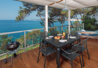 Terrasse på Lanterna Home Seaside chalet med havudsigt, spisebord, grill og trædæk under solsejl.