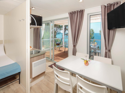 Innenaufnahme des Lanterna Home Seaside Chalets mit Esstisch, Terrasse und Meerblick in Kroatien.